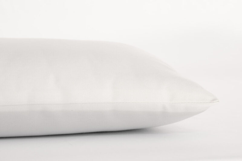 Child's wool pillow in white cotton encasement against plain background