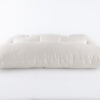 Tufted pillow in white cotton encasement on against white backdrop