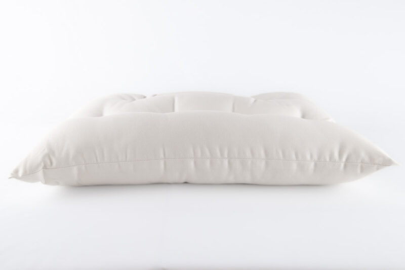 Tufted pillow in white cotton encasement on against white backdrop