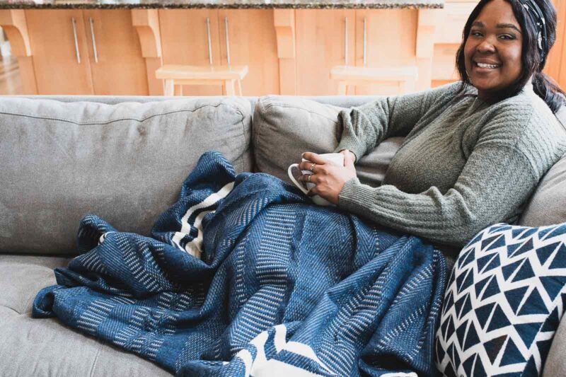 Woman on couch with organic Cirrus blanket