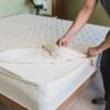 Man unzipping white cotton mattress cover from organic wool mattress.