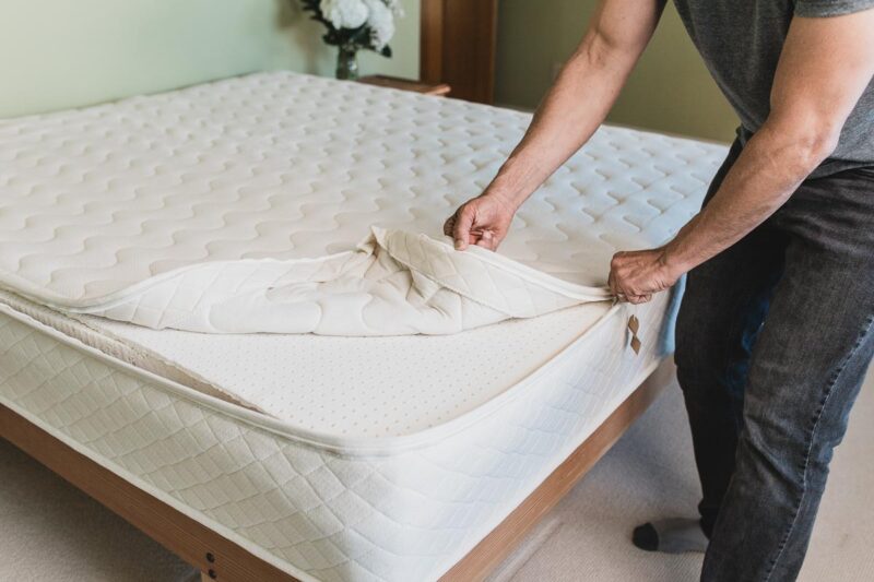 Man unzipping white cotton mattress cover from organic wool mattress.