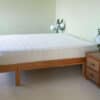 Side view of mattress with nightstands and floral arrangements.