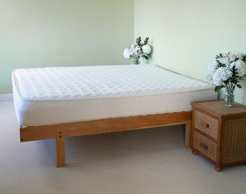 Side view of mattress with nightstands and floral arrangements.