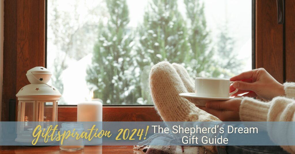 A scene of a woman reclining with a cup of tea and her feet up on a windowsill looking out over a wintry forest scene.