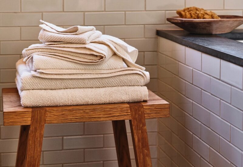 Coyuchi organic cotton Air Weight towels in Alpine White and Fog on wooden pedestal