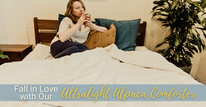 A woman reclines in bed with a hot drink.
